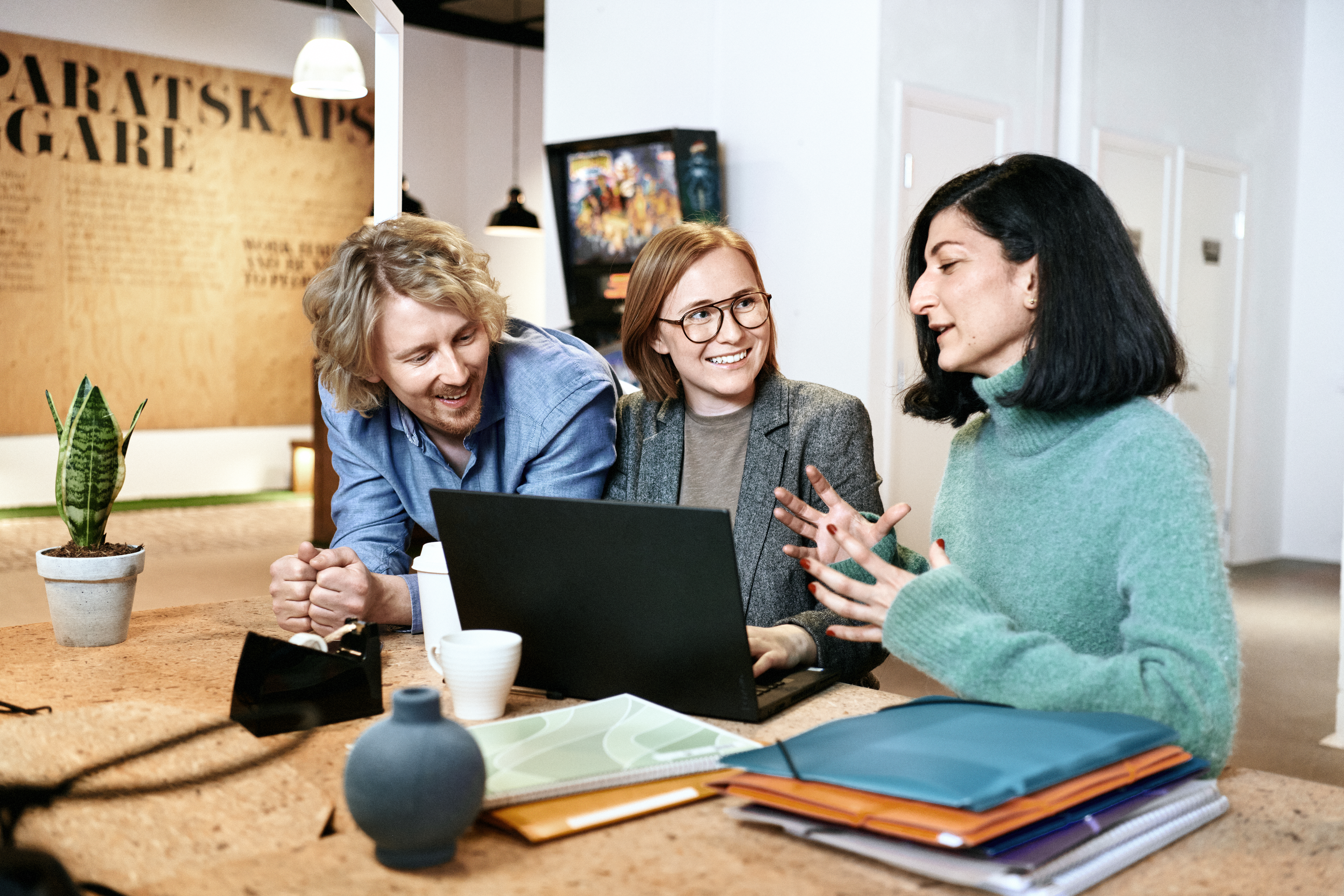 Two women and a man at a desk with a laptop.