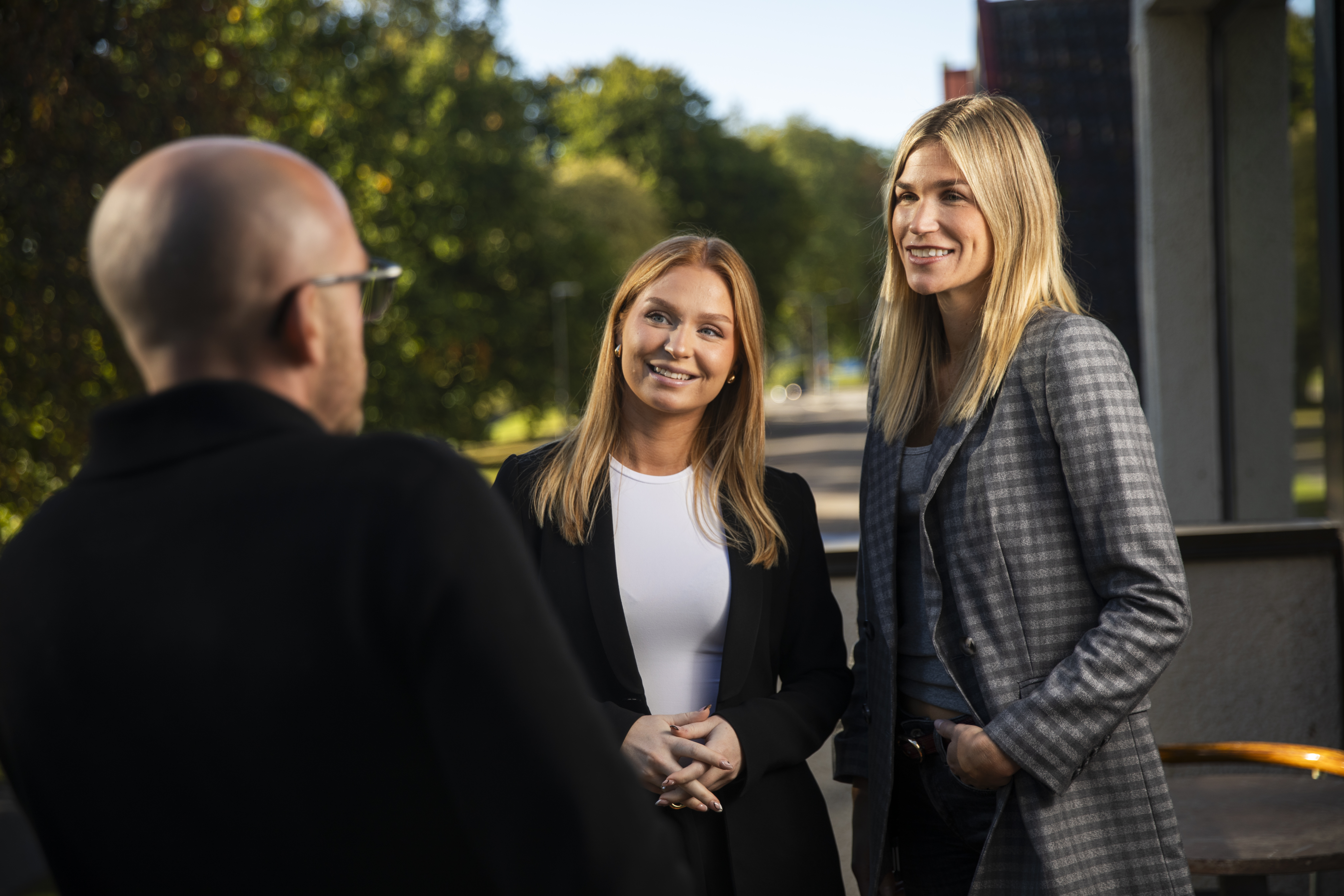 Tre kollegor står och pratar med varandra på balkongen